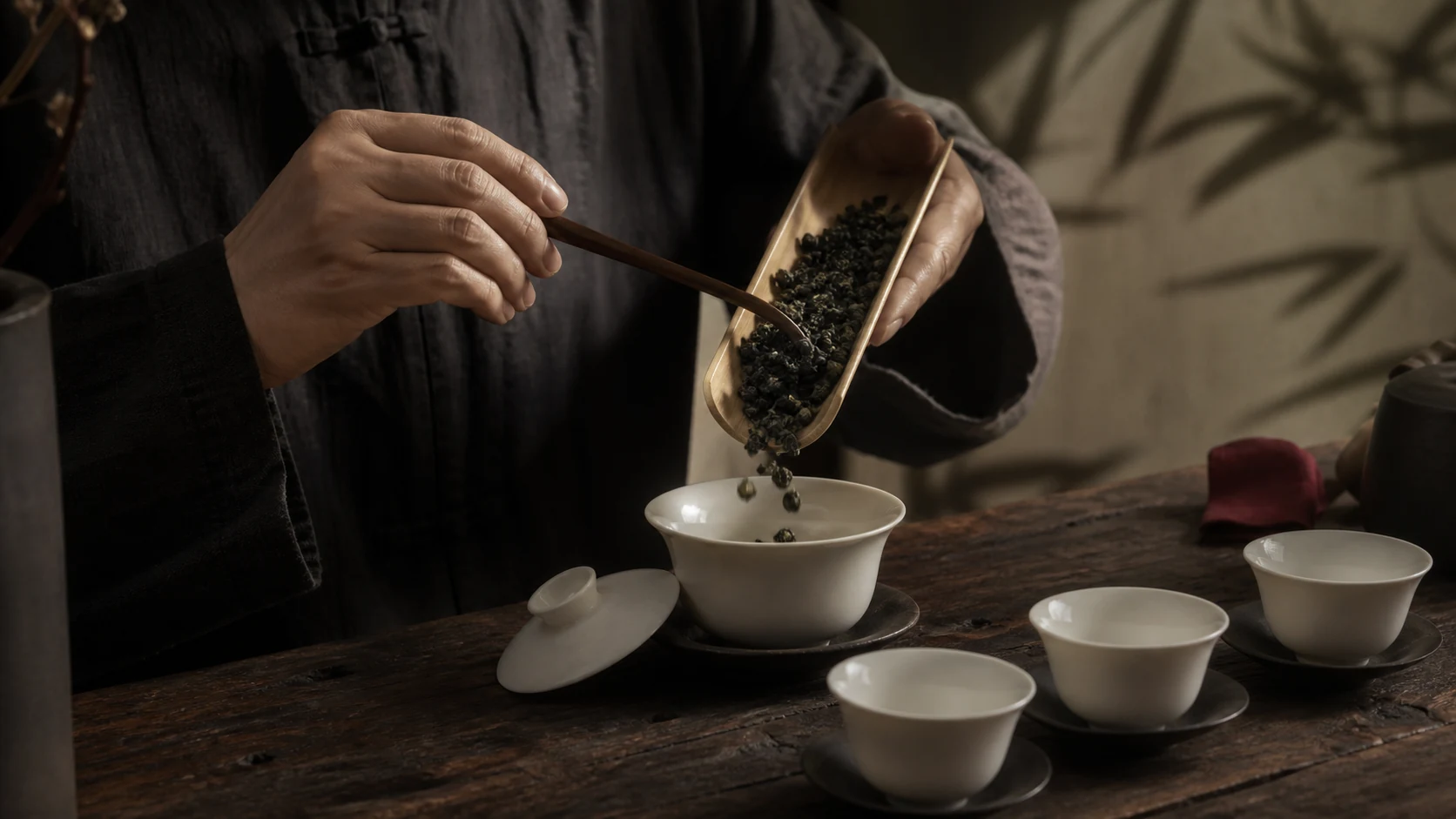 Dry leaf tipped from a bamboo scoop into the warmed gaiwan.
