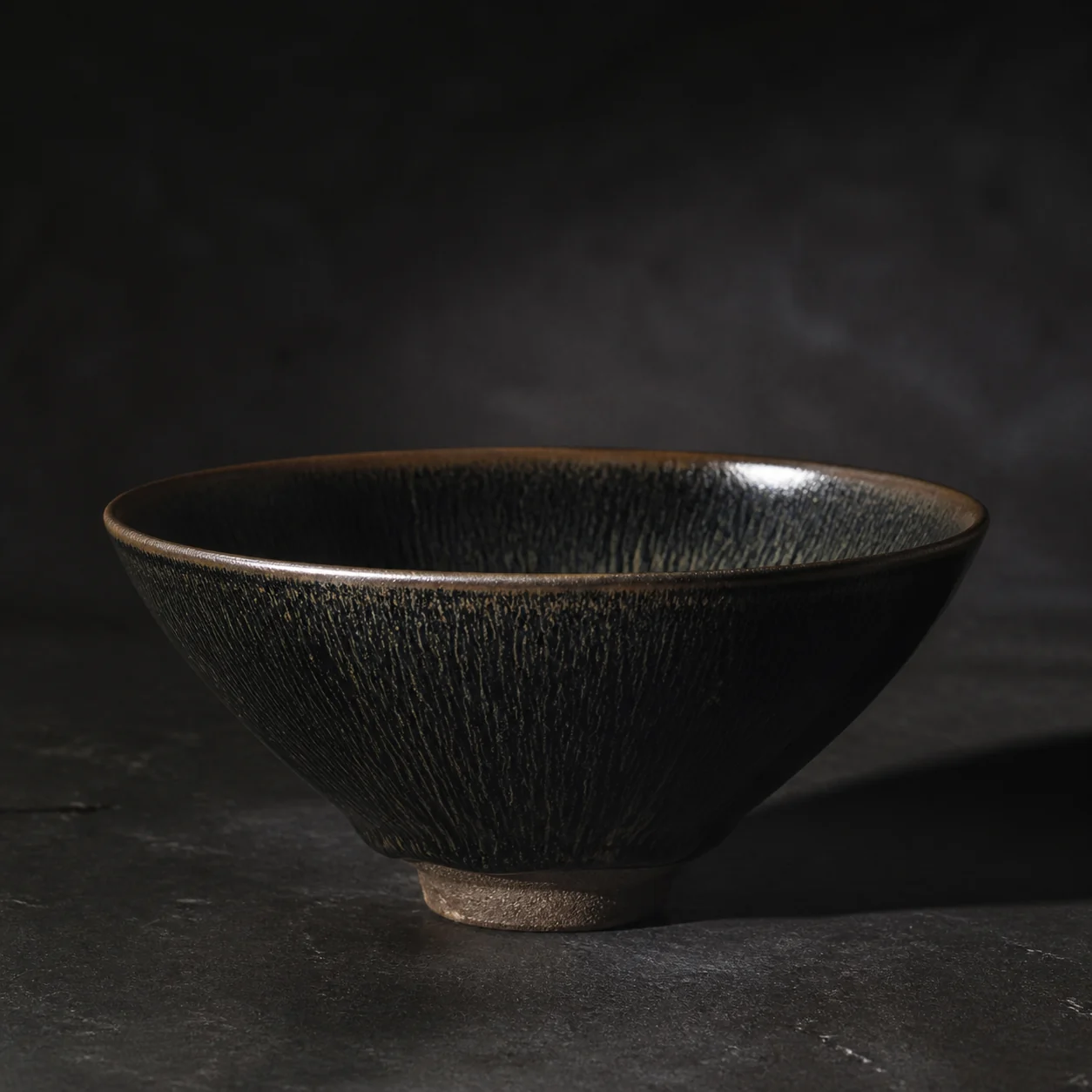 A black-glazed Jian ware bowl, its iron-rich surface catching the light.