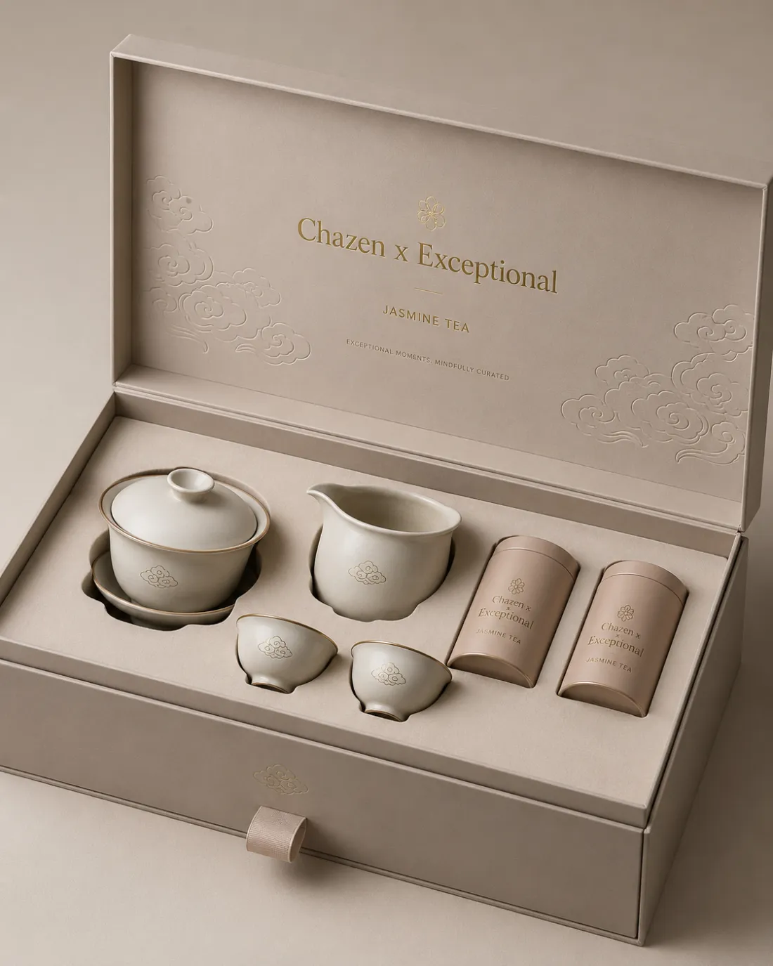 An open taupe gift box; the lid reads Chazen x Exceptional, Jasmine Tea in gold above a faint cloud motif. Inside sit a matching gaiwan, a pitcher, two cups and two tins in the same taupe.